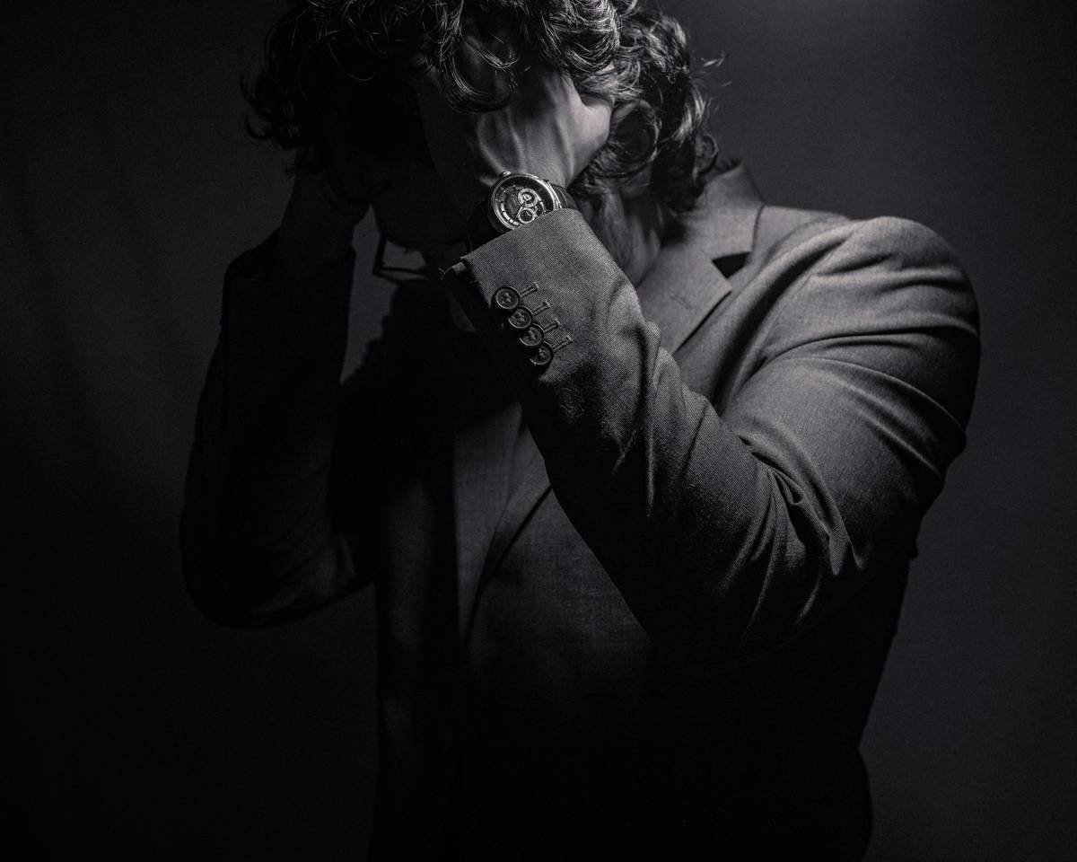a man in a suit covers his face with his hands