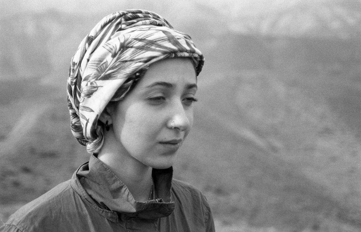 A woman gazes with mountains in the background.