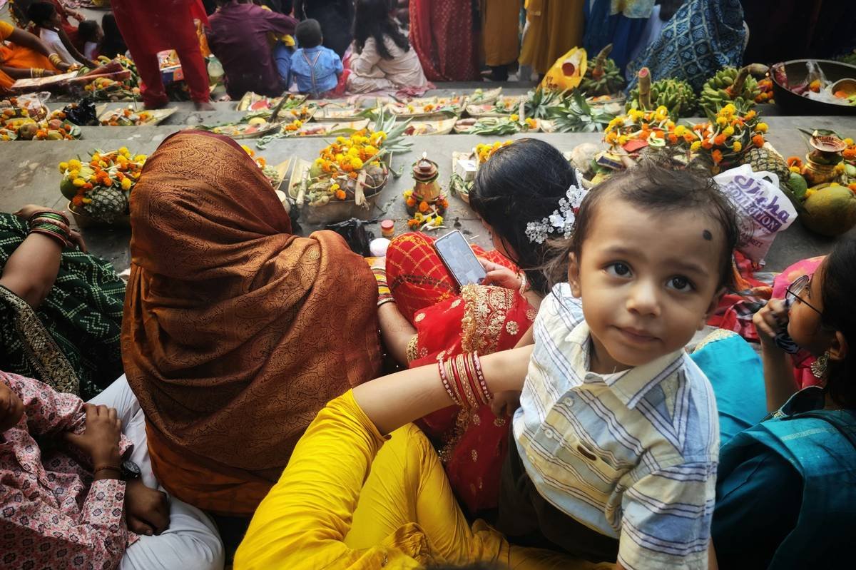 A young child looks at the camera amidst a crowd.