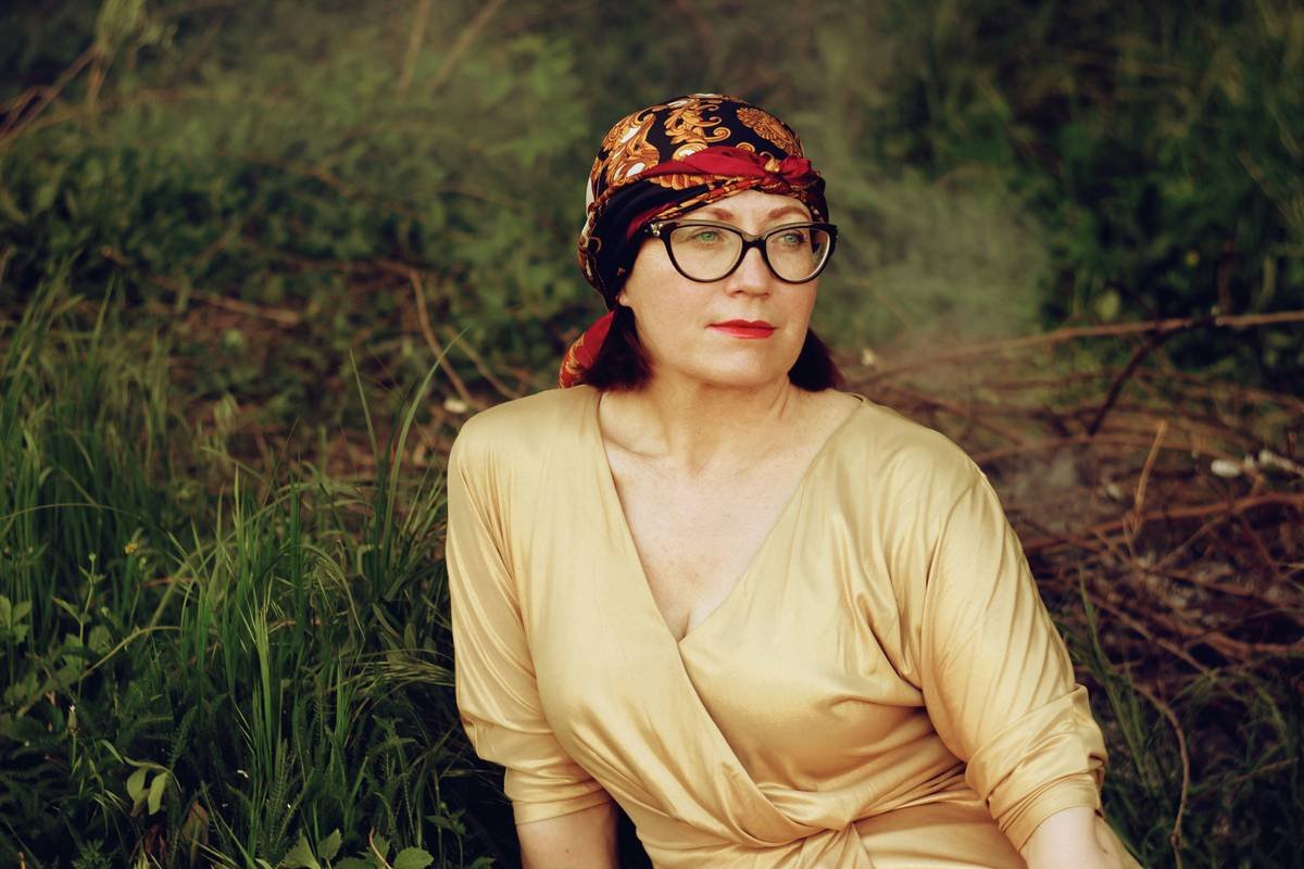 A brooding woman in her mid 50s sitting on the grass in the shimmering golden dress and headscarf. P. S. If you like my work and want to support me, there is an option to buy a coffee (paypal link in profile). Thank you!